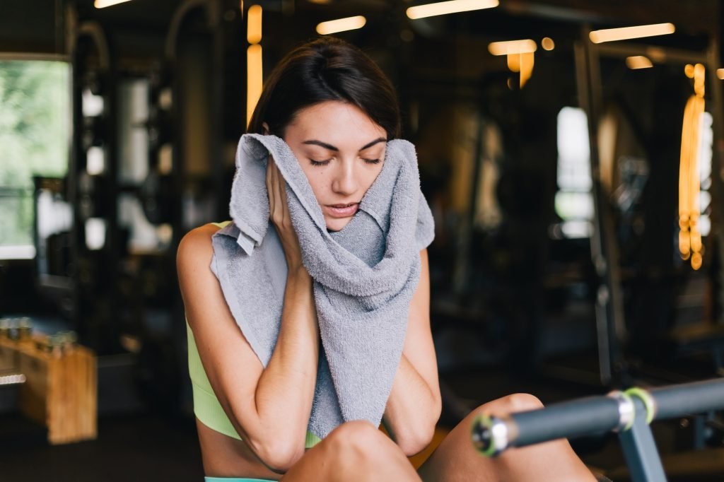 Fit caucasian beautiful woman in fitting sport wear at gym tired sweating clean face with towel