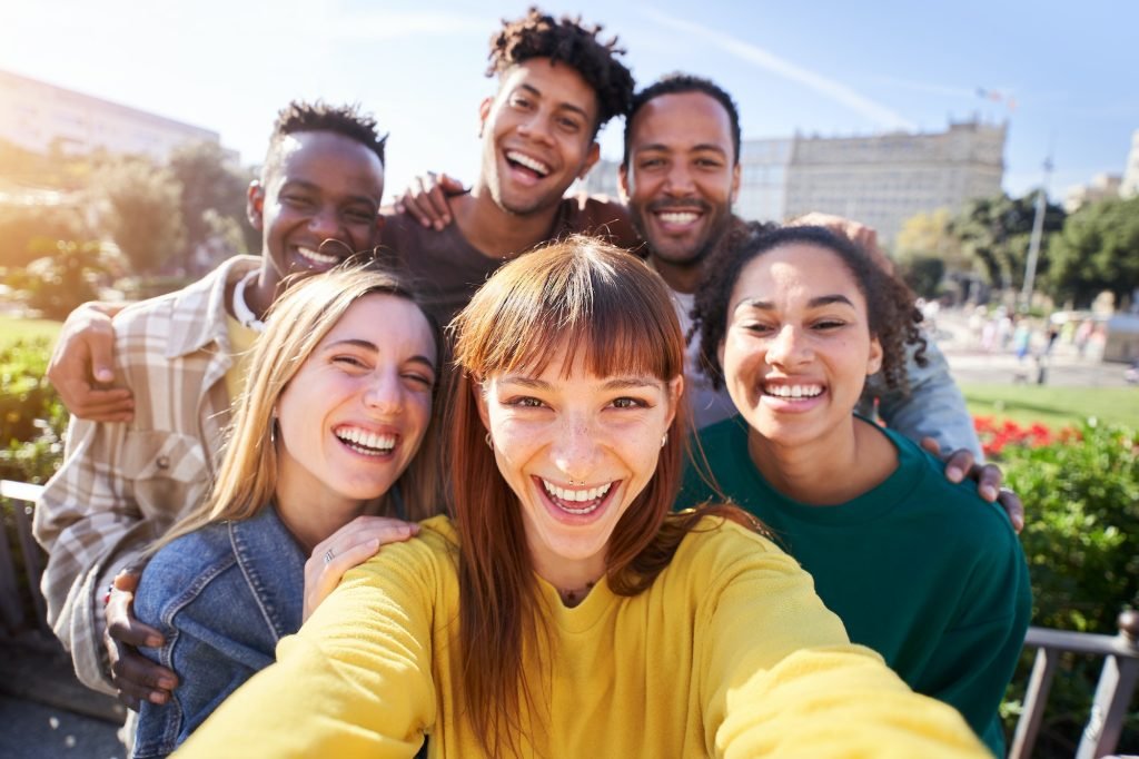 Group of happy friends posing for a selfie on a spring day as they party together outdoors