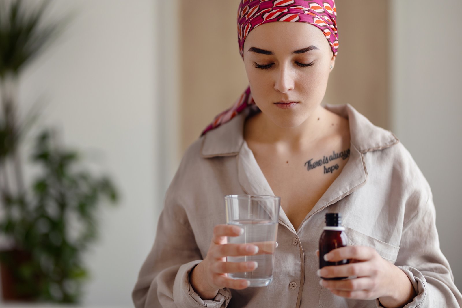 Young woman with cancer taking pills, cancer awareness concept.